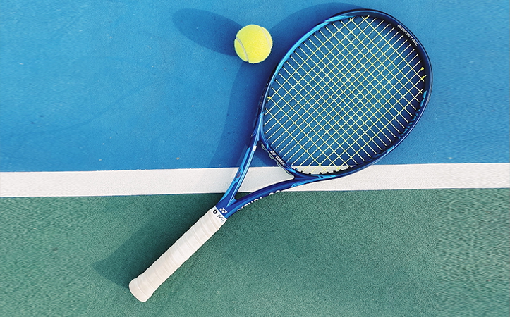 Blue tennis racquet and yellow tennis ball on tennis court